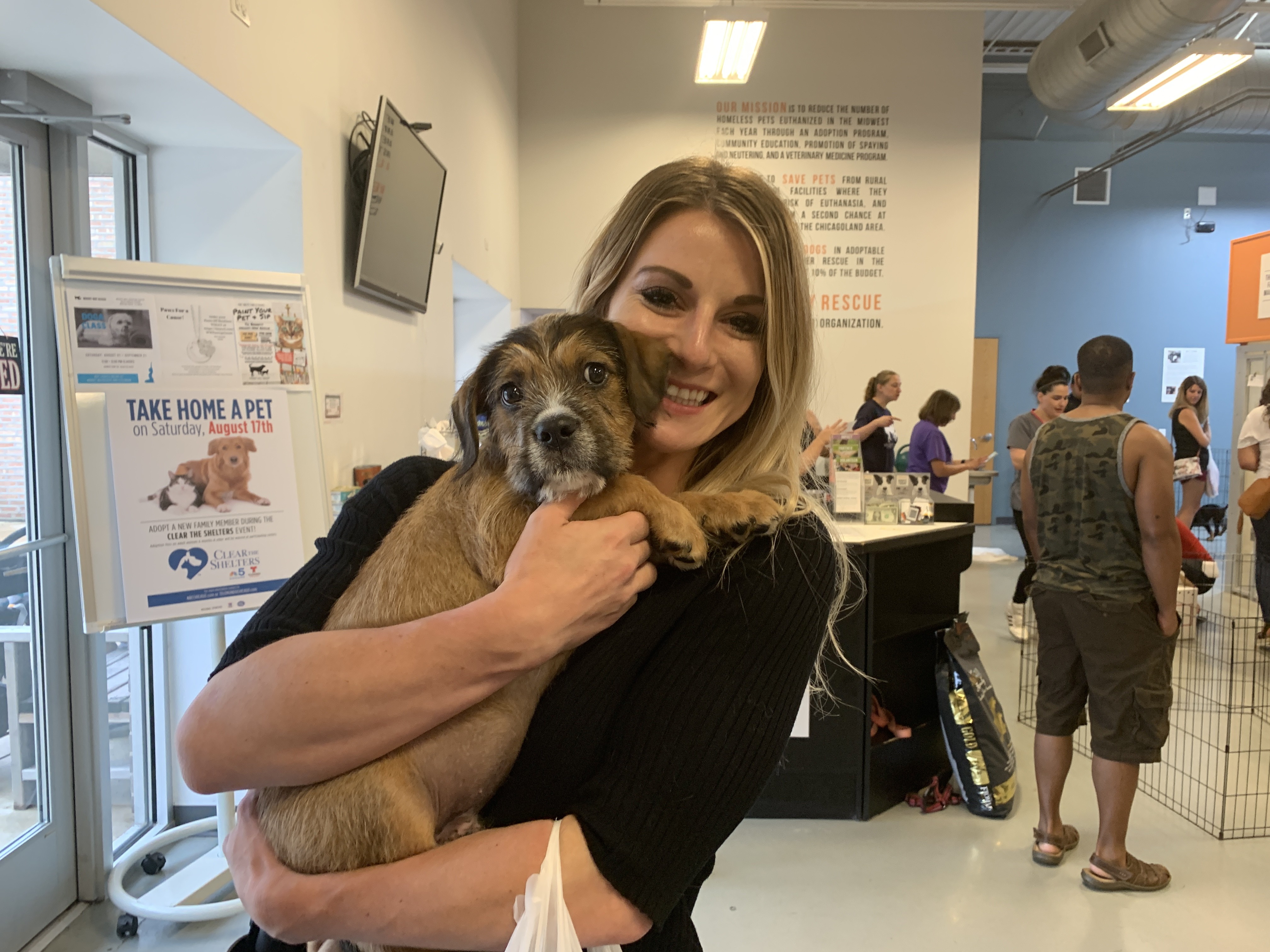 A woman holding a puppy at a Clear The Shelters adoption event